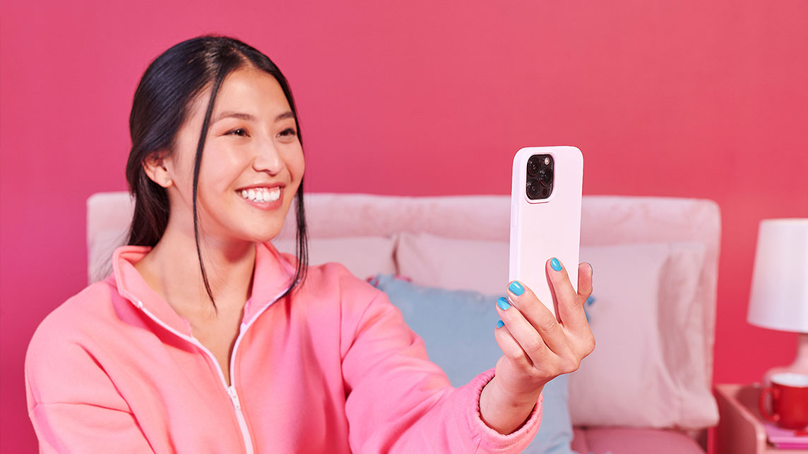 A person holding a mobile device, smiling and having a video interview.