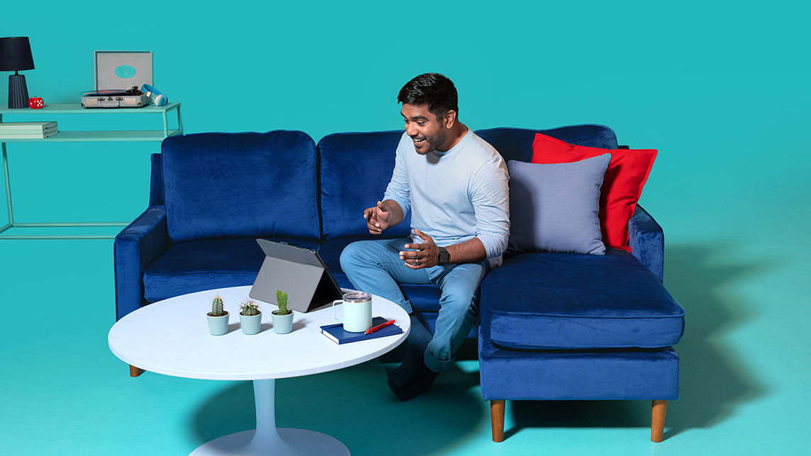 A person sitting on a couch and having a video interview in front of their tablet device.