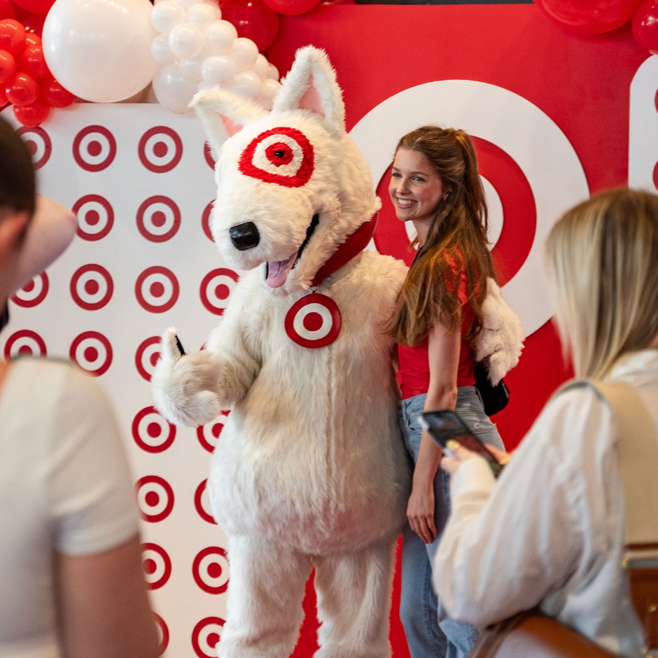 Someone poses for a picture with the Target Bullseye mascot in front of the Target logo.