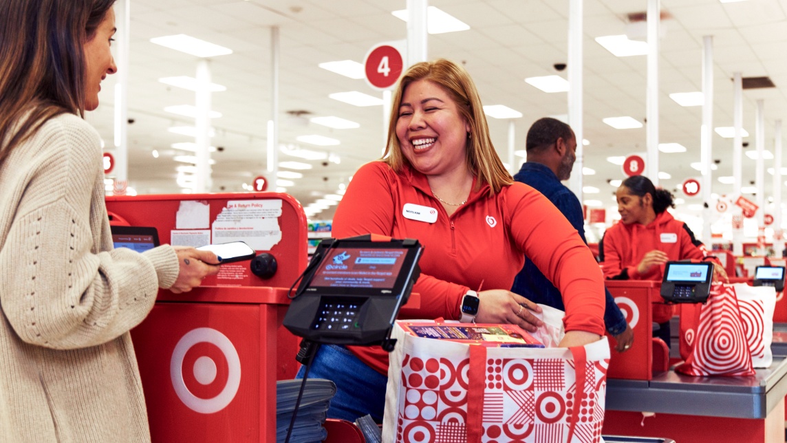 A Target team member smiles while placing items in a reusable Target bag at checkout.