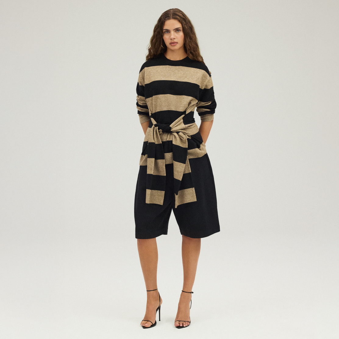Model in bold black-and-tan striped knit with matching wrap detail and wide shorts, styled with heels for a modern, effortless look.]