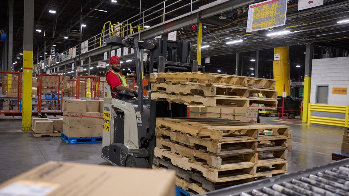 A Target team member operates machinery to move freight in a supply chain facility.