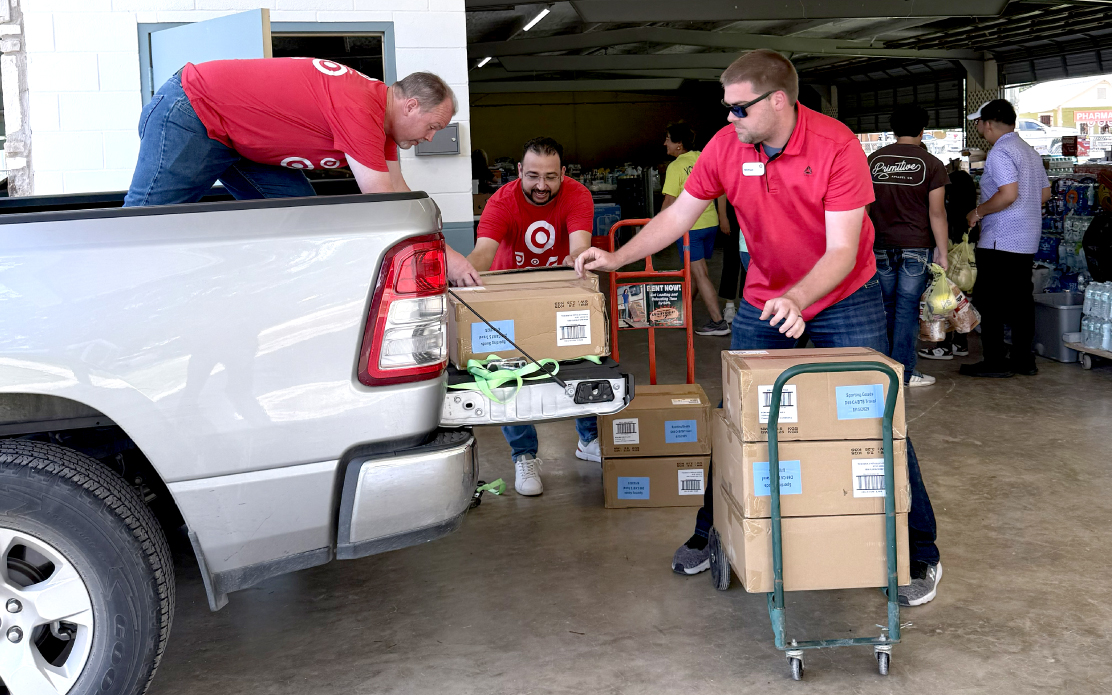 Three adults load donations into the back of a pickup truck.