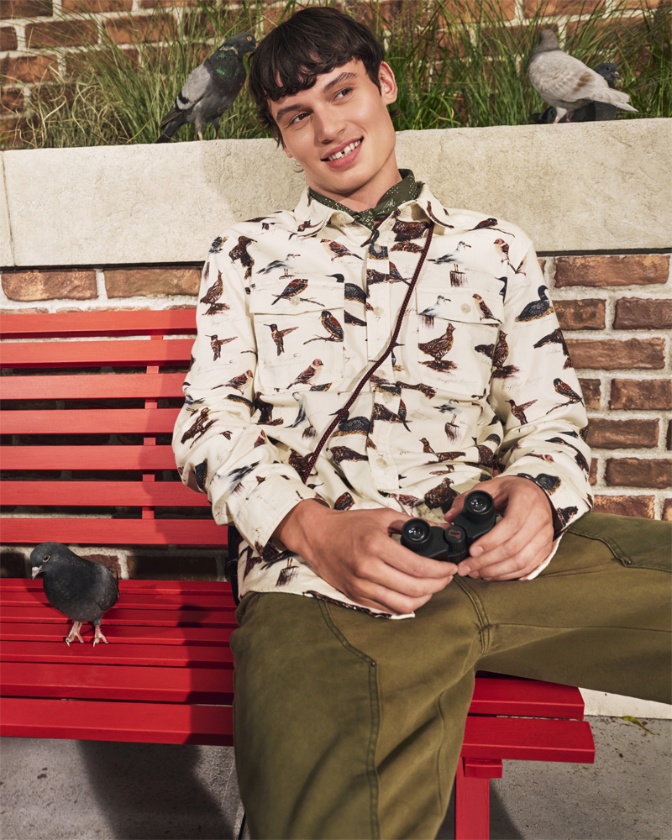 Model styled in apparel and holding binoculars from the Woolrich x Target collection