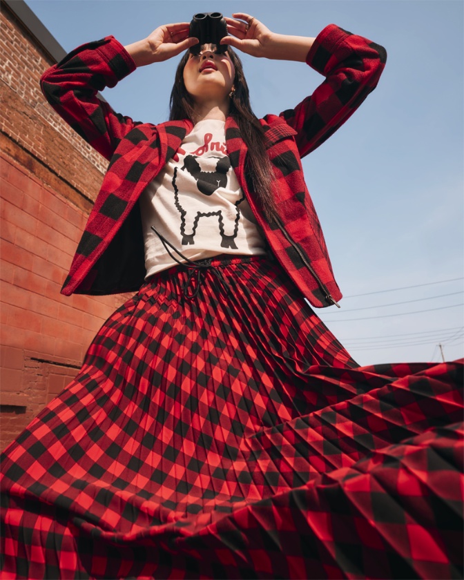 Model styled in apparel and holding binoculars from the Woolrich x Target collection